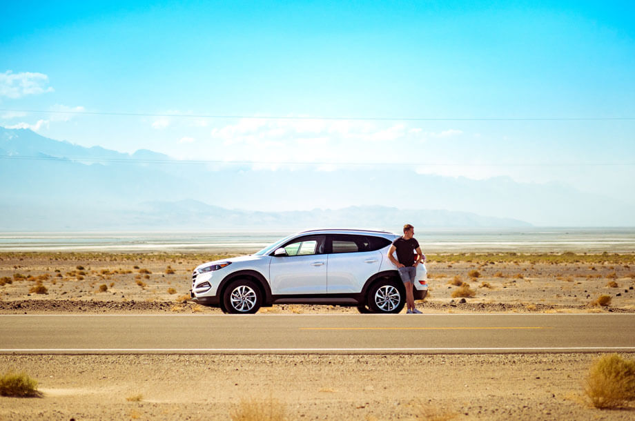 Man standing beside car on side of lonely road | Allenbrook Auto Insurance